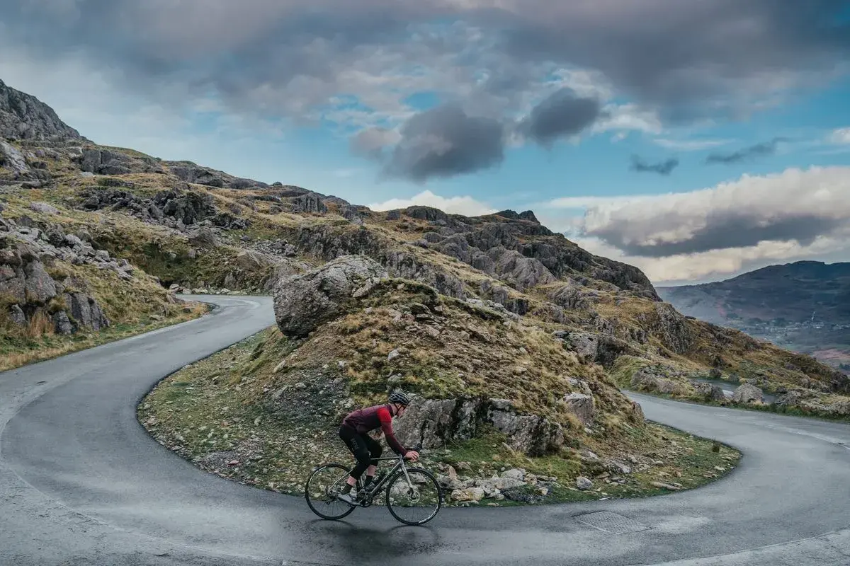 Ciclista en una carretera sinuosa en un paisaje montañoso, disfrutando de su aventura de España en bicicleta.