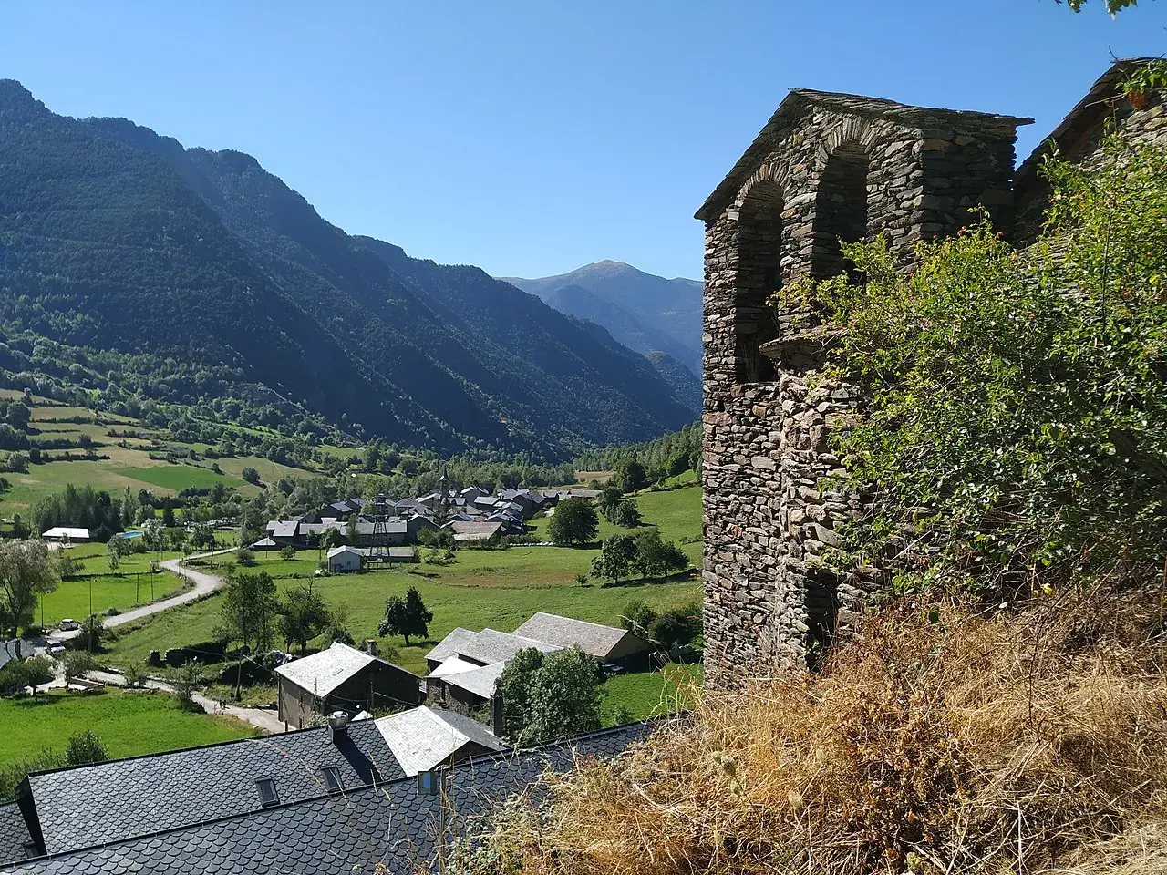 Vista del pueblo de Vall Ferrera con su campanario de piedra y montañas verdes al fondo.