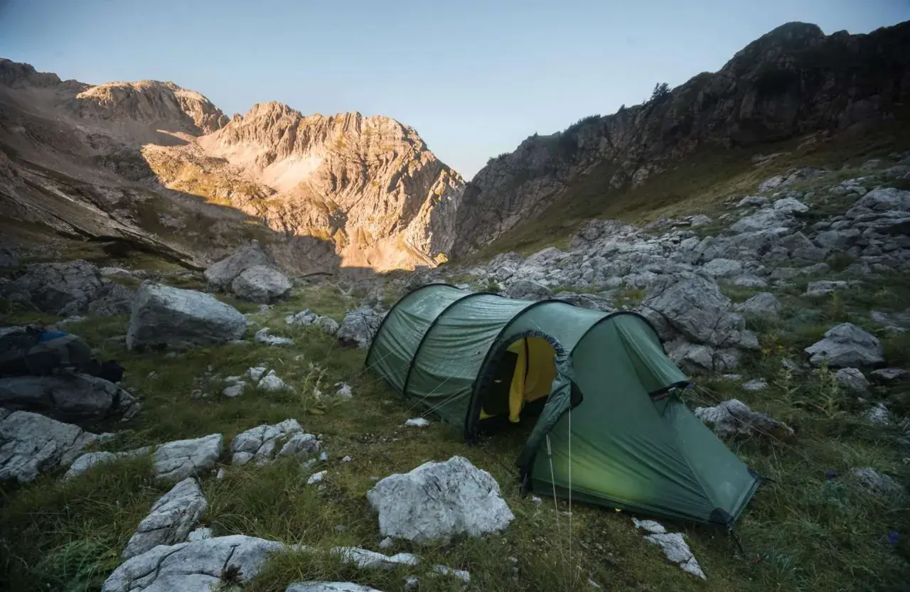 Tienda de campaña verde en un paisaje montañoso rocoso, ideal para acampada libre España.