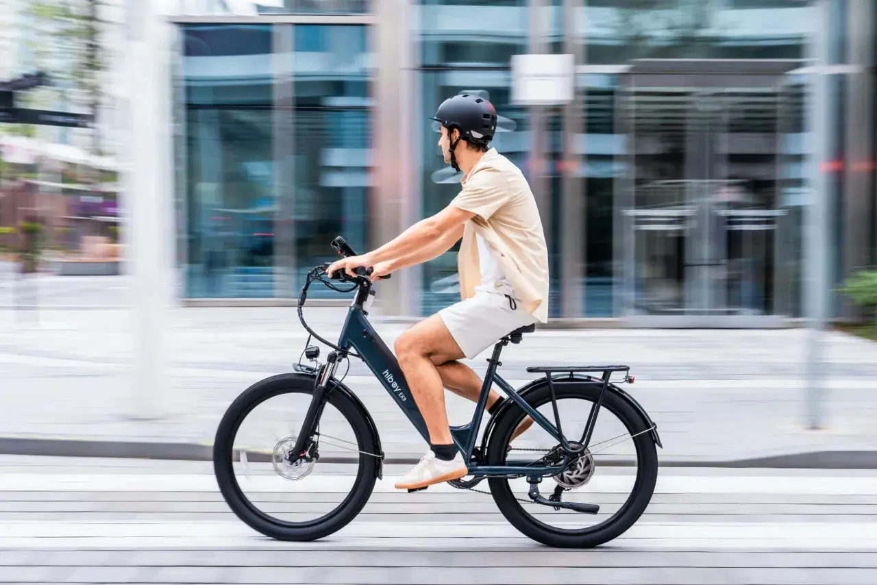 Hombre en bicicleta eléctrica, disfrutando de una marcha cicloturista urbana. El fondo borroso sugiere movimiento rápido y moderno.