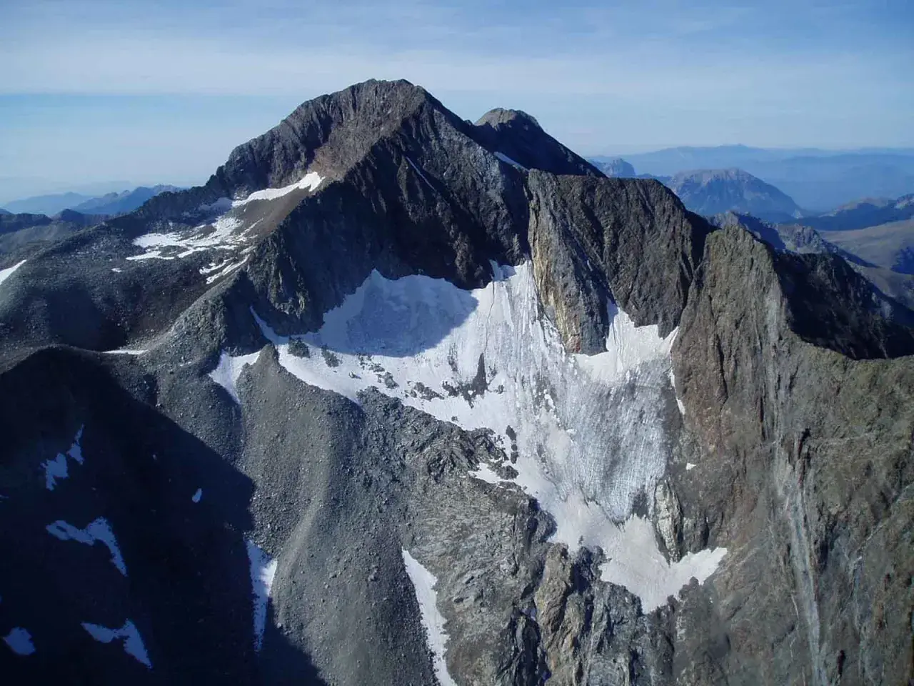 Majestuoso pico perdiguero cubierto de nieve y roca, con un glaciar que desciende por sus laderas.