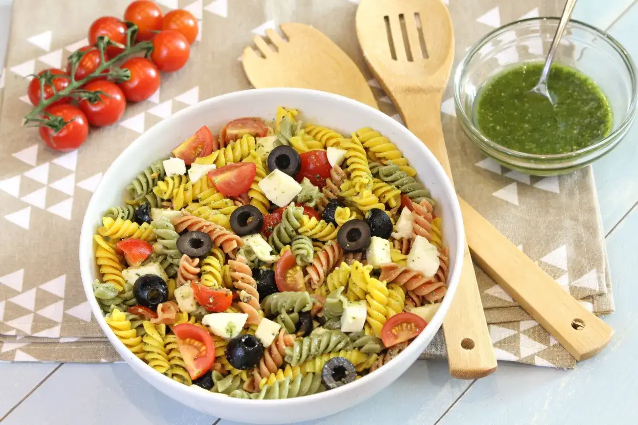 Ensalada de pasta tricolor con tomates, aceitunas y queso, perfecta como comida para llevar en autocaravana.