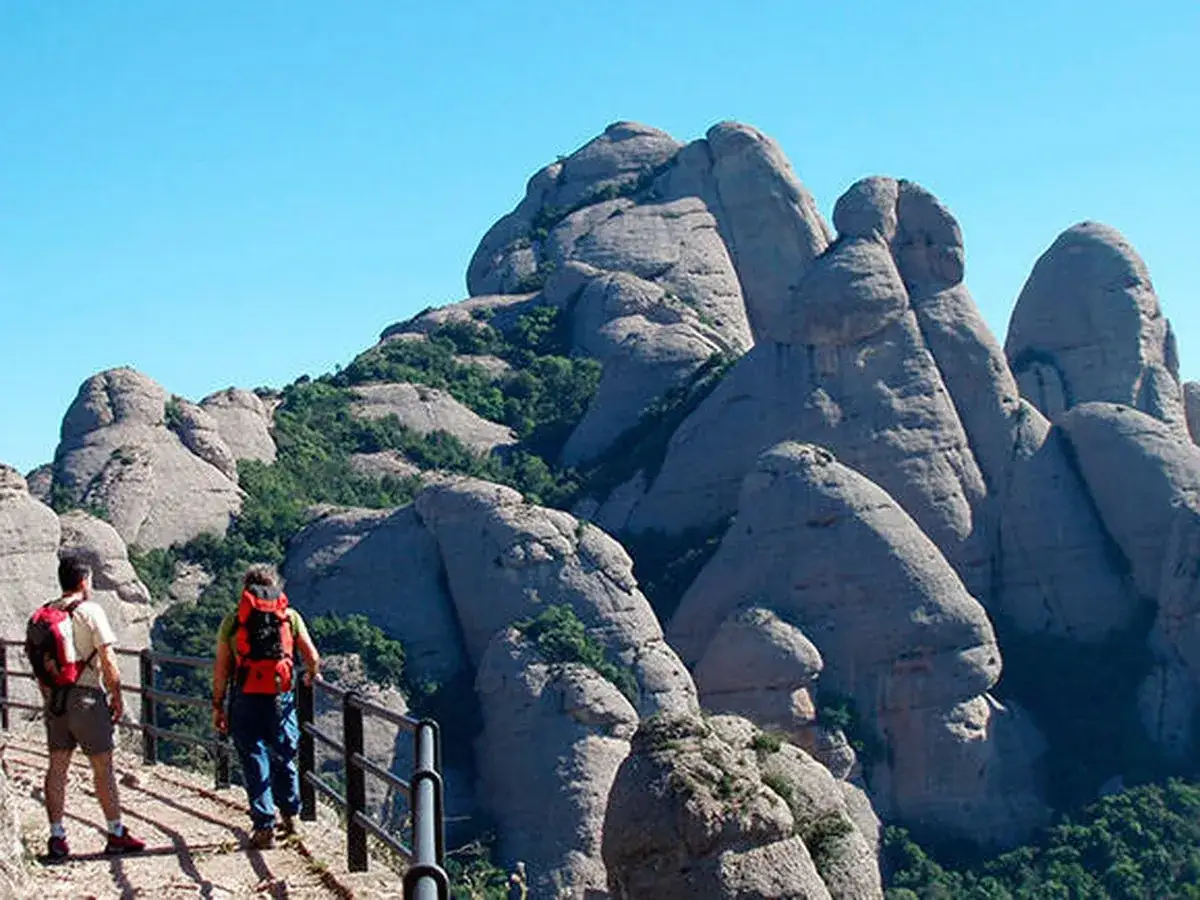 Senderistas exploran el parc natural de la muntanya de Montserrat, admirando sus imponentes formaciones rocosas.