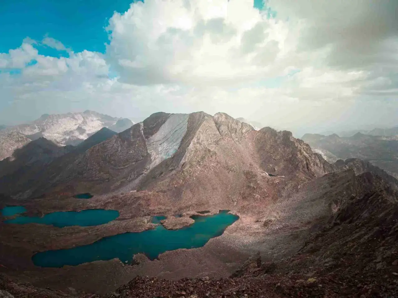 Paisaje montañoso con lagos turquesa, como si fueran los picos del infierno en un día nublado.
