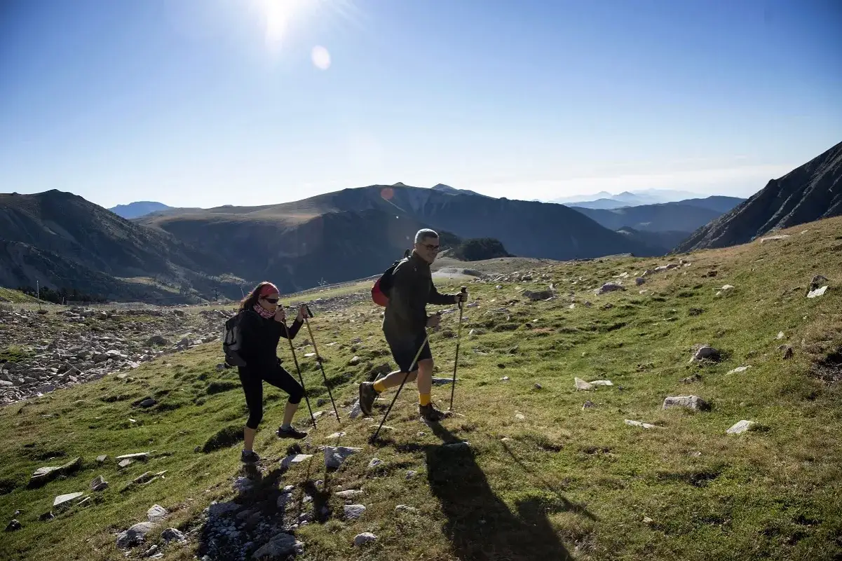 Pareja haciendo senderismo en un paisaje montañoso, con la gra de fajol como telón de fondo.