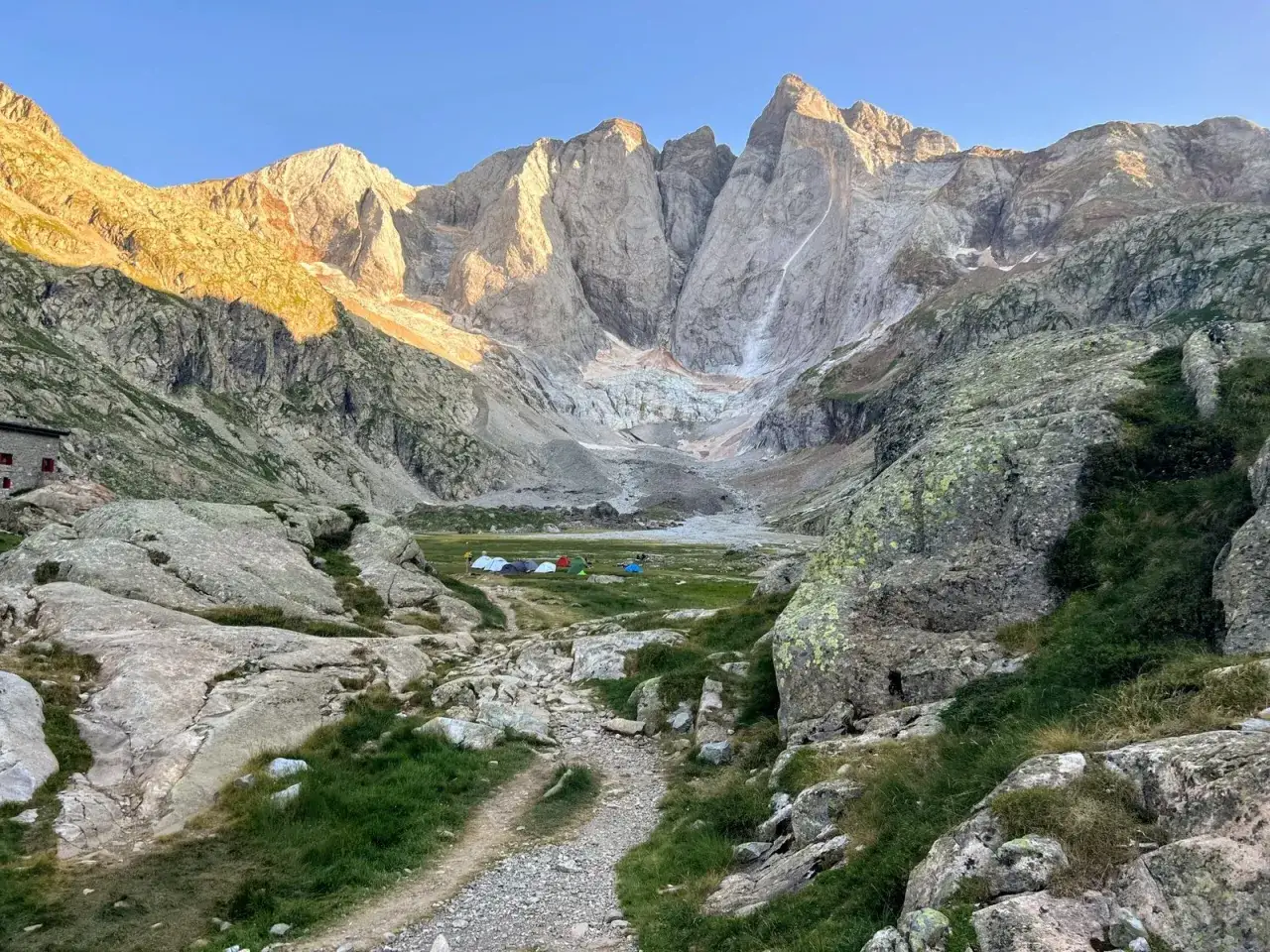 Majestuoso Vignemale desde Bujaruelo, con un campamento de tiendas en el valle y el sol iluminando las cumbres rocosas.