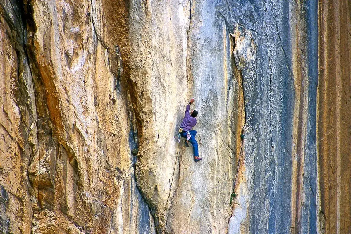 Un escalador desafía la pared rocosa, un chorro de adrenalina en su ascenso.