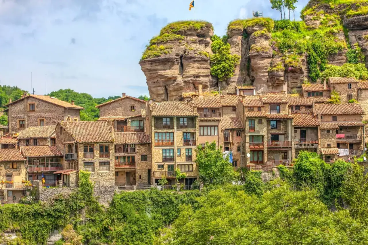 Pueblo de piedra con tejados rojos, anidado bajo un acantilado. Las rutes per Osona te llevan a este lugar con encanto.