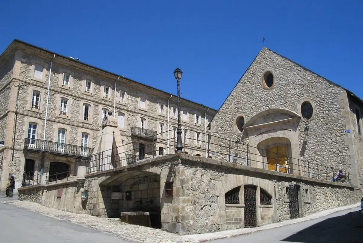 Edificio de piedra y monumento en Mont Louis bajo un cielo azul.