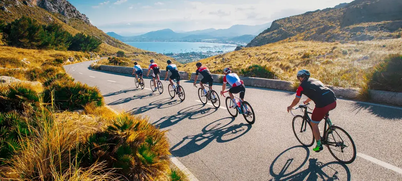 Ciclistas disfrutan de un recorrido escénico en España en bicicleta, con vistas al mar y montañas.