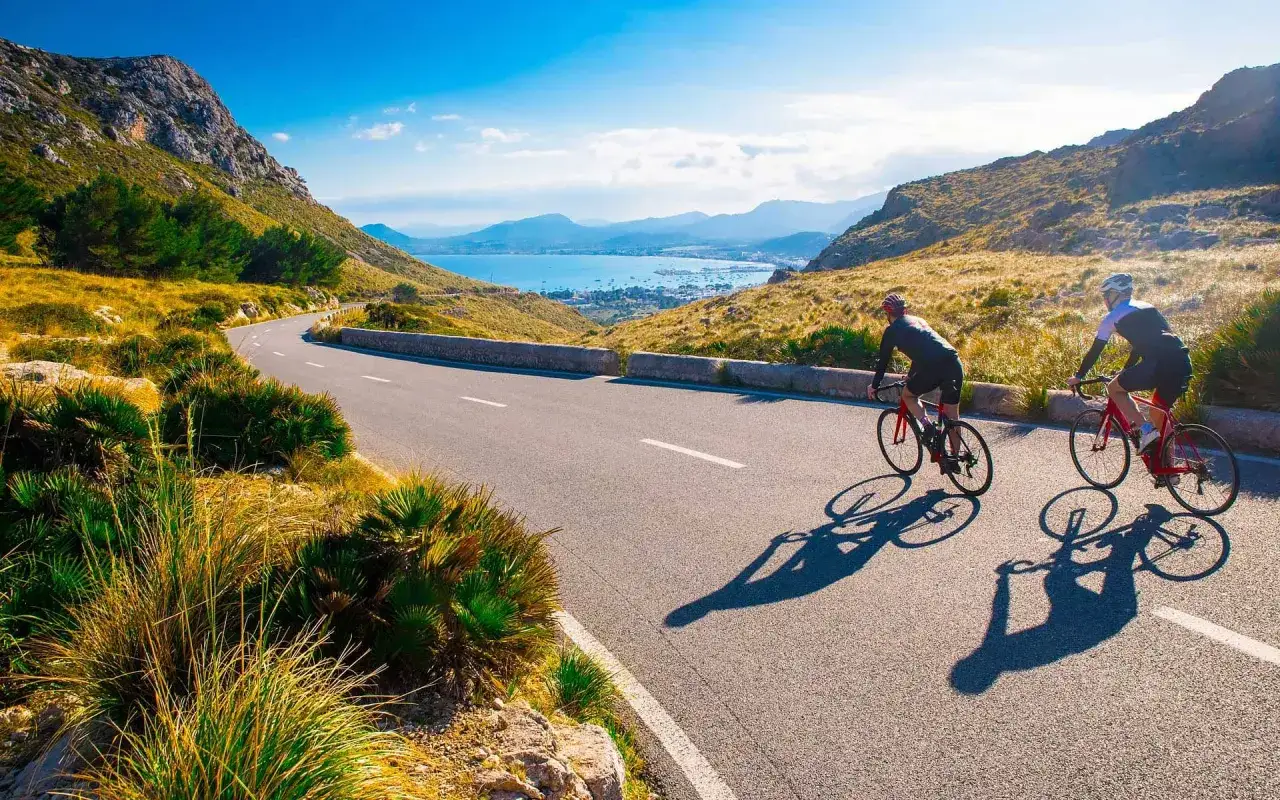 Dos ciclistas disfrutan de una ruta escénica en Mallorca en bici, con vistas al mar y montañas.