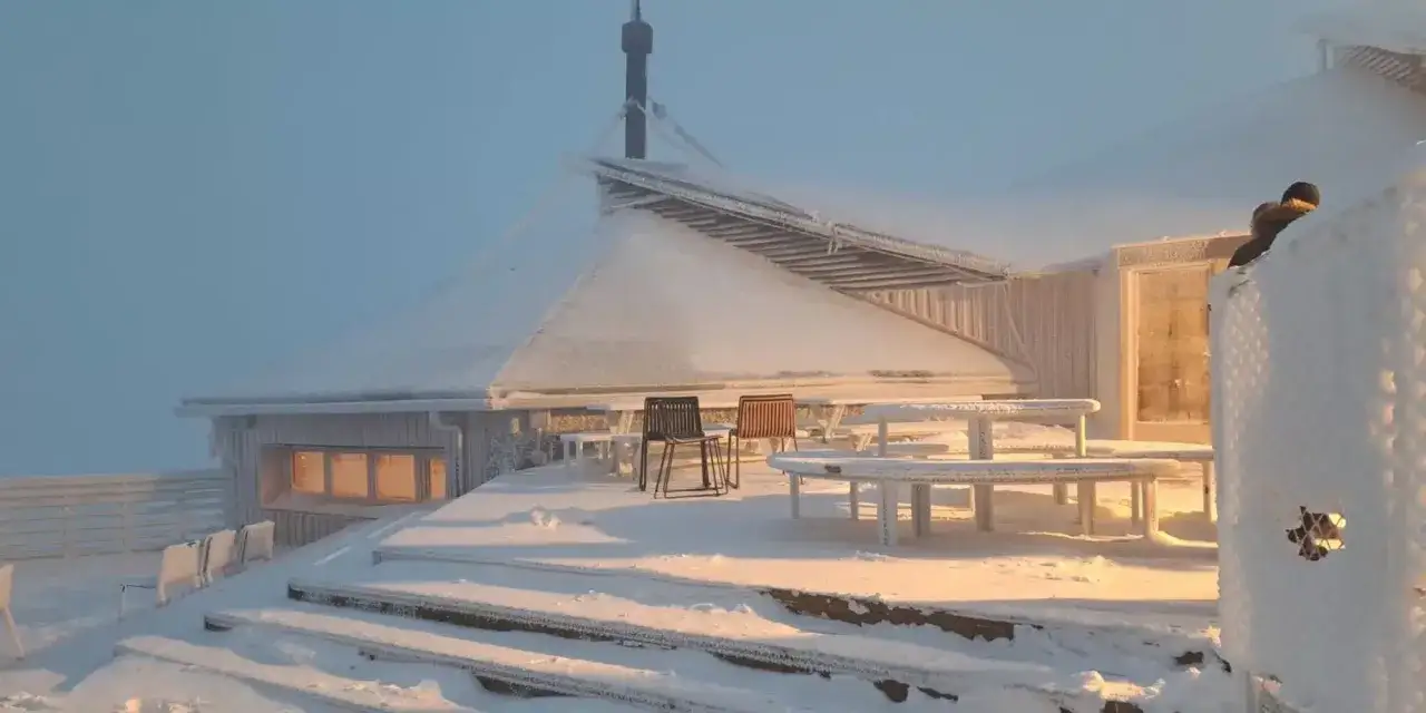 Terraza de un refugio de montaña cubierto de nieve y hielo. Mesas y sillas esperan a los visitantes en esta tosa d'alp.