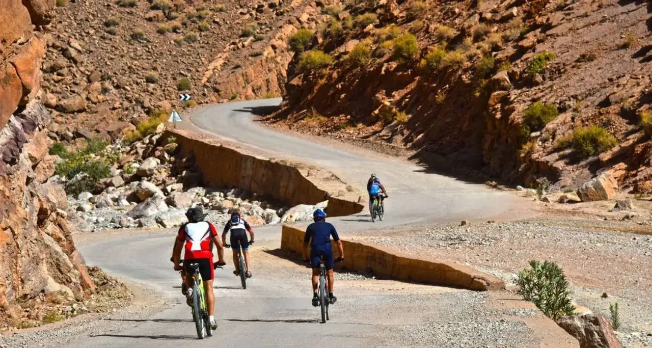 Ciclistas disfrutan de una ruta escénica de marruecos en bici por un camino montañoso y rocoso.