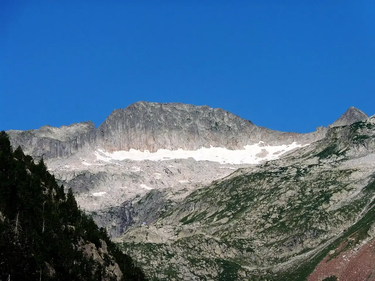 Majestuoso pico Mulleres con nieve en su cima, bajo un cielo azul intenso.