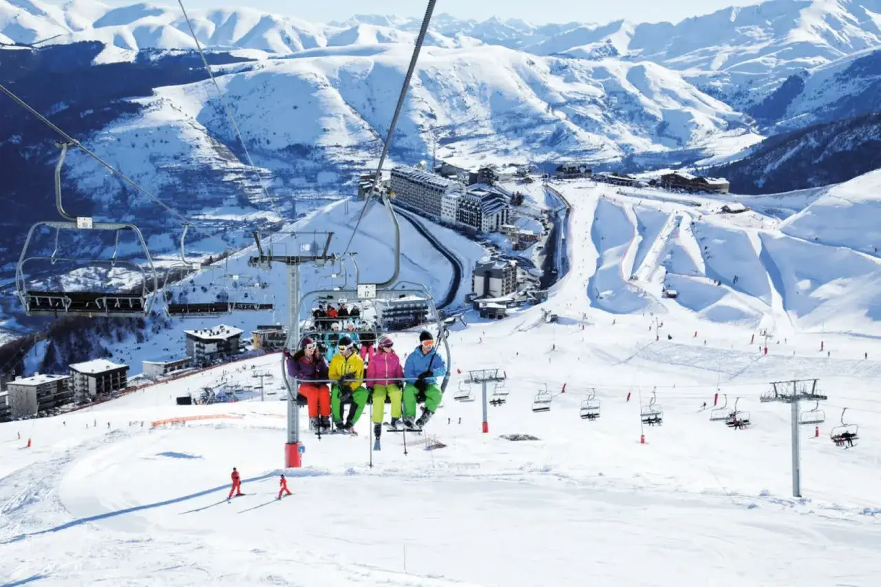 Gente en telesilla disfrutando de las pistas de esquí en Saint Lary Soulan, con montañas nevadas de fondo.